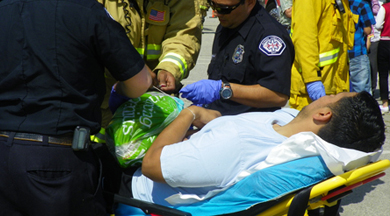 COC EMT学生与消防和救护人员在救护车担架上。