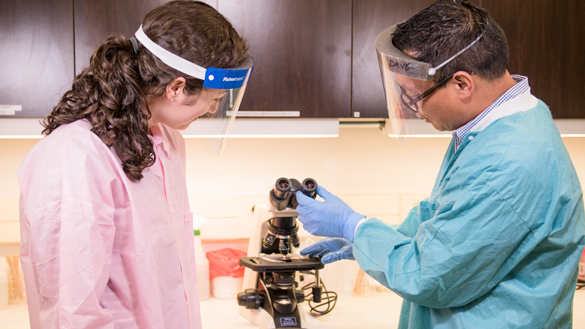 医学实验室技术员学生和导师带着显微镜。