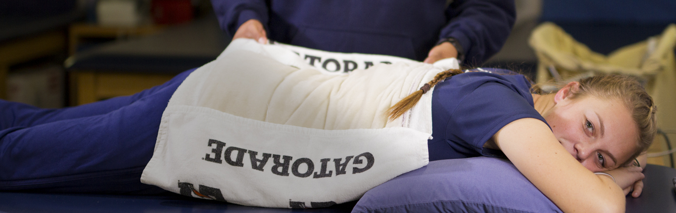 运动医学教师应用热垫在运动员的损伤后背。